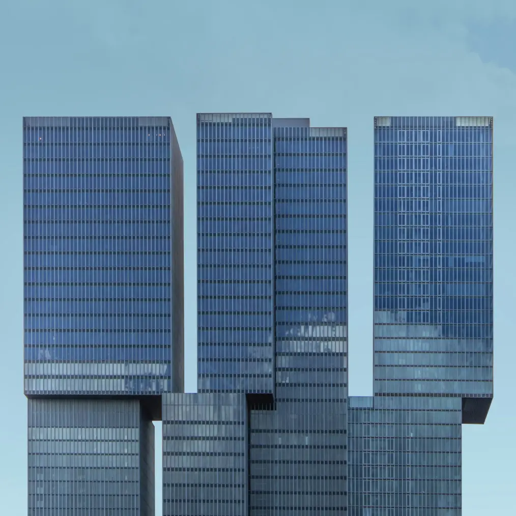 Minimalistische architectuurfoto van donkerblauwe, blokvormige kantoorgebouwen tegen een egale, lichtblauwe lucht.